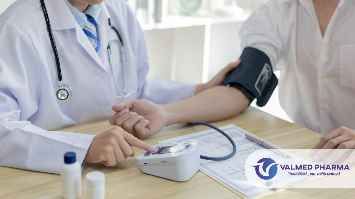 Healthcare professional checking a person’s blood pressure with an upper-arm cuff and digital monitor, with Valmed Pharma branding.