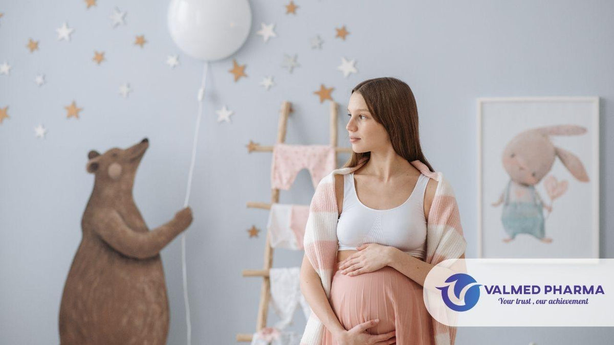 Woman holding her belly in a nursery decorated with stars and animal illustrations, with Valmed Pharma branding.