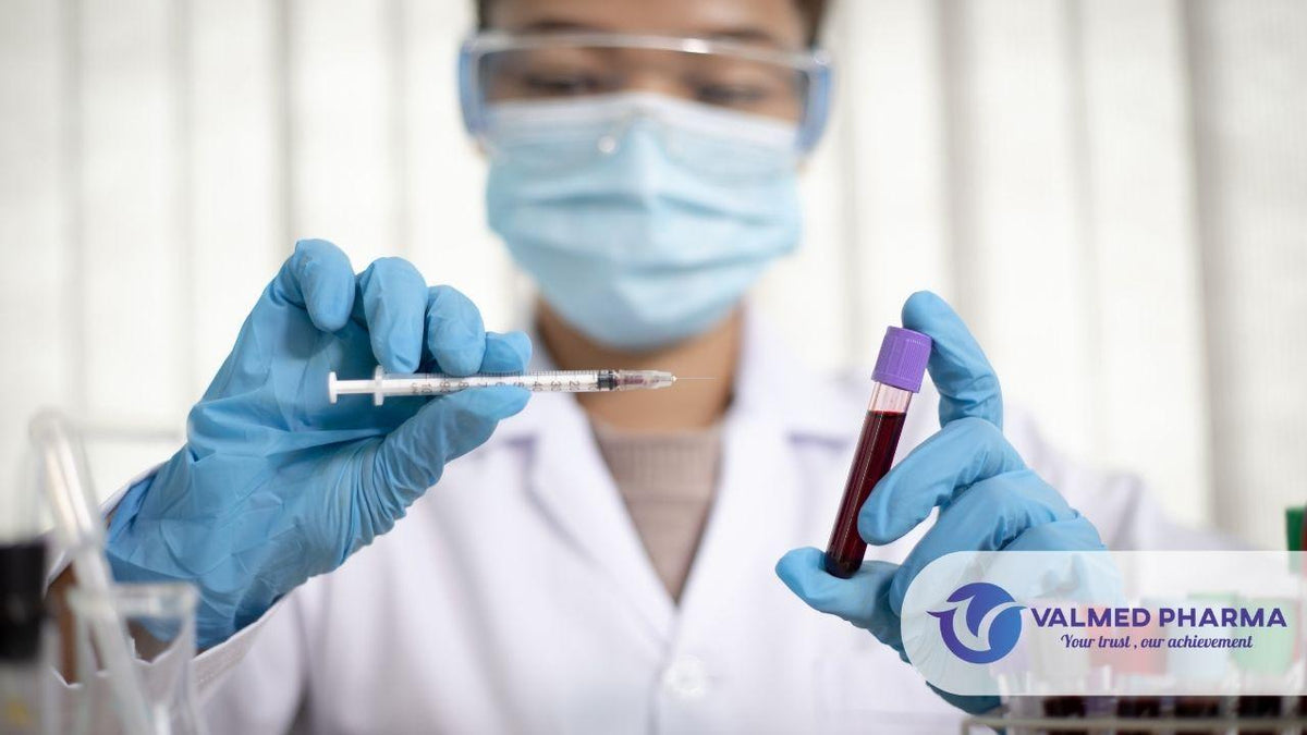 Laboratory professional wearing protective equipment holding a syringe and a blood sample tube, with Valmed Pharma branding.