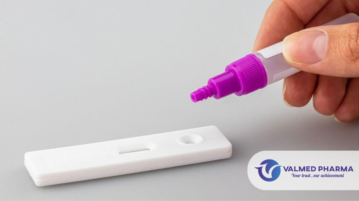 Hand holding a sample dropper above a rapid test cassette, with Valmed Pharma branding.