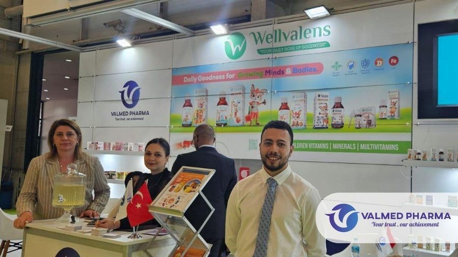 People at the Valmed Pharma and Wellvalens exhibition booth with supplement displays and branded signage.