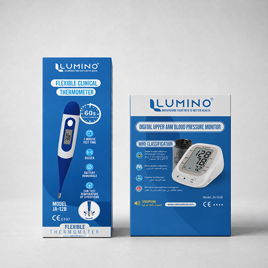 Two retail boxes from LUMINO displayed side by side on a light gray studio background: a blue flexible clinical thermometer box on the left and a blue digital upper arm blood pressure monitor box on the right.